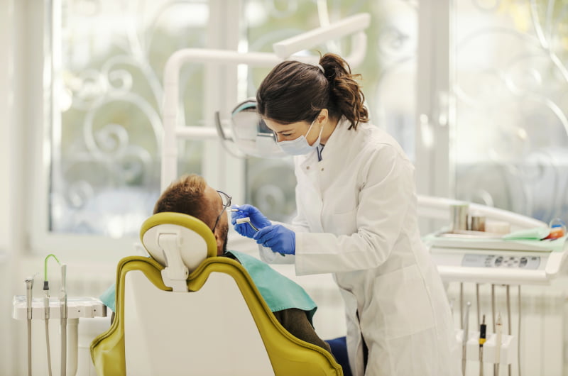 Dentist providing treatment for a patient receiving a fixed full-arch dental restoration