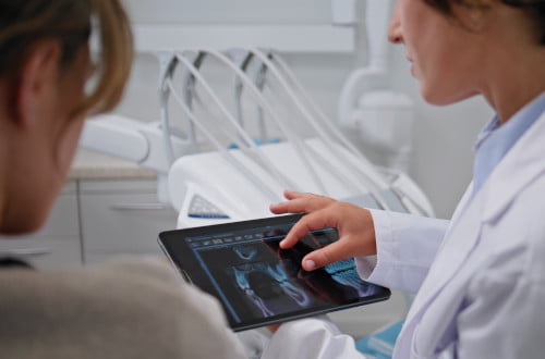 A dentist explaining restorative dental treatment options such as fillings and root canal therapy.