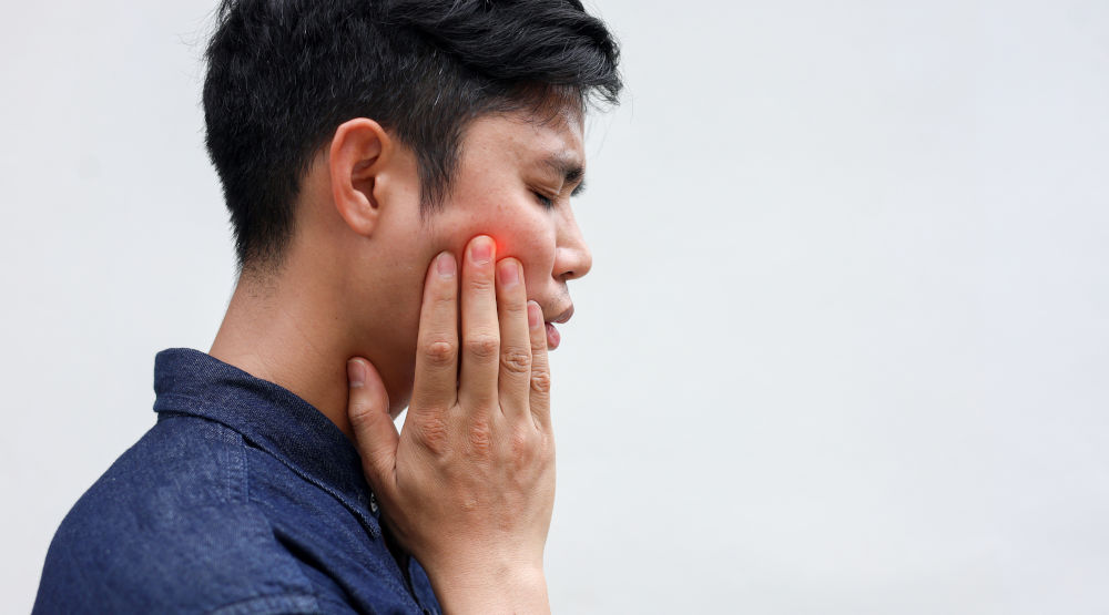 Man experiencing back tooth pain when chewing and applying pressure