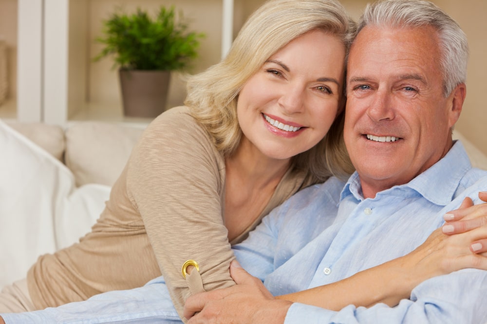 Happy senior couple with confident smiles after full-arch dental treatment