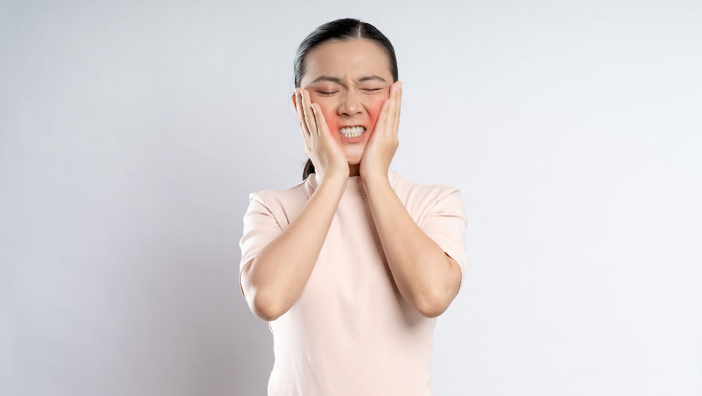 Woman with severe tooth pain when biting down due to a dental problem